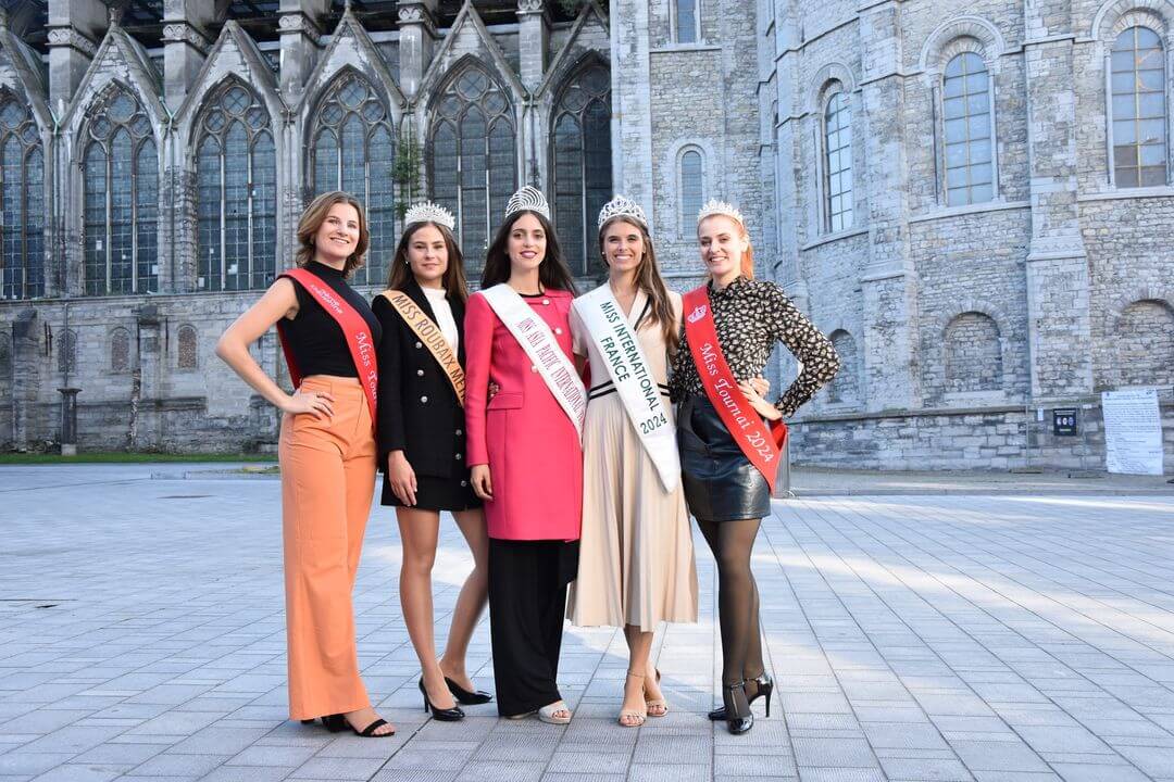 Camille Platroz, Julie Goyé, et Wanessa Osewska visitant des lieux emblématiques de Tournai, Belgique, entourées par des participants locaux.