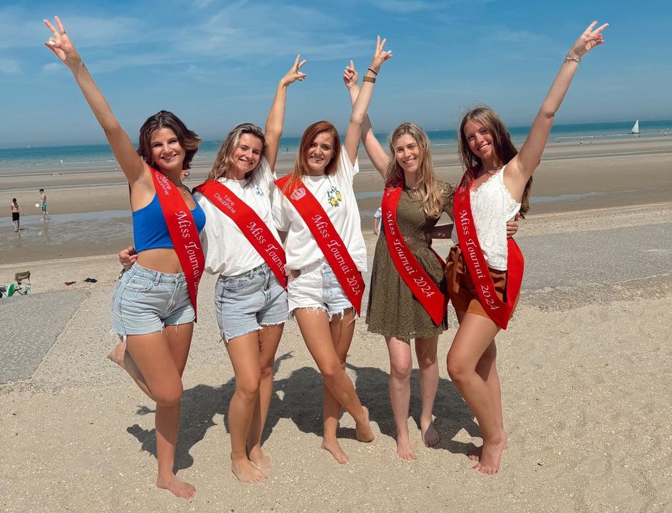 Miss Tournai Léa, Lola, Catherine, Cyrielle, et Kimberly posent sur la plage ensoleillée de La Panne, portant des bracelets offerts par Lola.