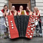 Miss Tournai 2023 à l'événement "accordéon moi j’aime", entourée de ses dauphines et d'un public enthousiaste.