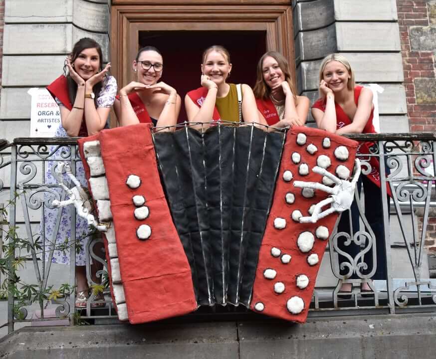Miss Tournai 2023 à l'événement "accordéon moi j’aime", entourée de ses dauphines et d'un public enthousiaste.