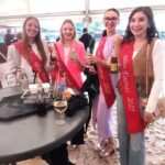 Miss Tournai souriante à l'inauguration de Tournai les Bains sous un ciel nuageux, décor bleu et blanc méditerranéen.