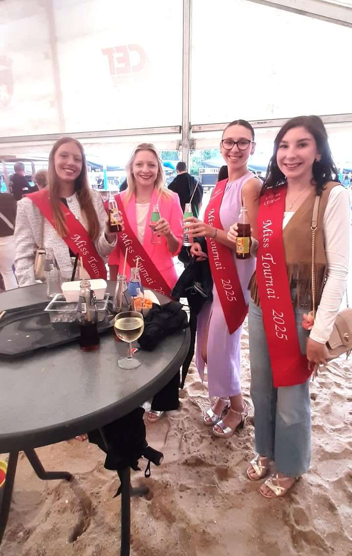 Miss Tournai souriante à l'inauguration de Tournai les Bains sous un ciel nuageux, décor bleu et blanc méditerranéen.