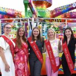 Miss Tournai à la Foire de Septembre, entourées d'attractions foraines et de gourmandises.