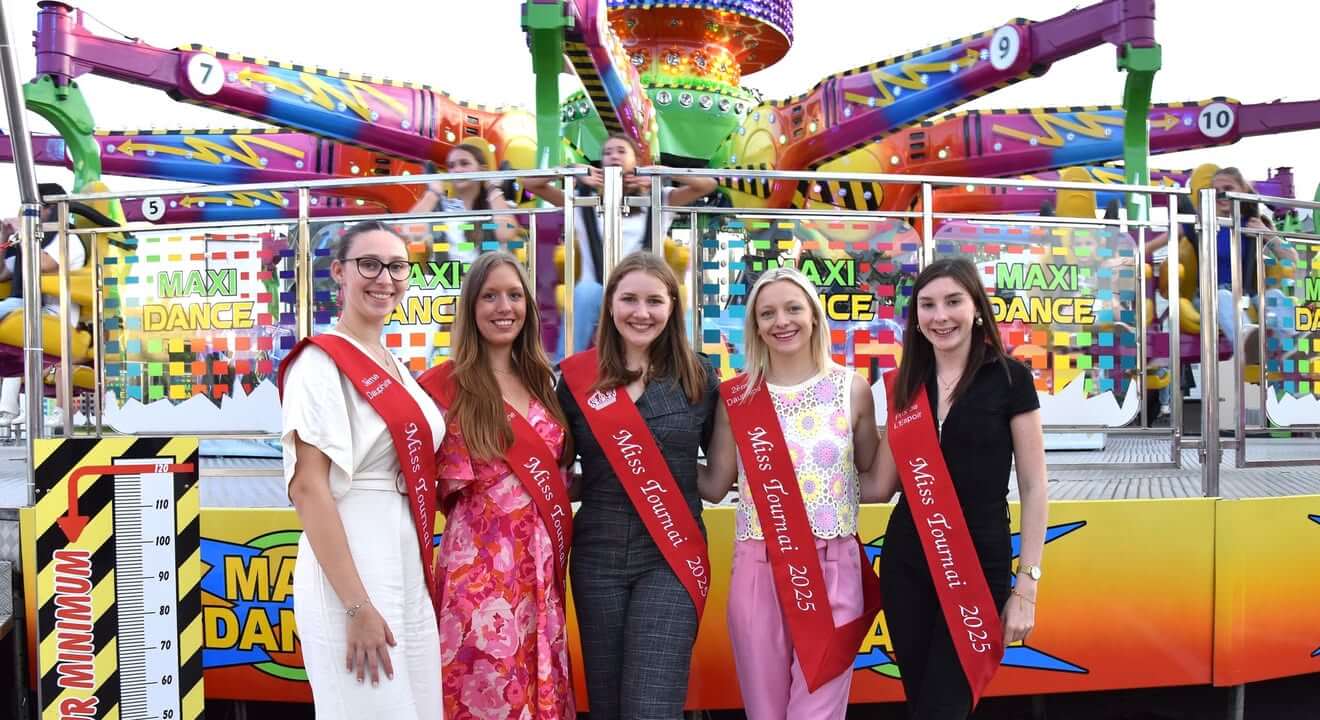 Miss Tournai à la Foire de Septembre, entourées d'attractions foraines et de gourmandises.
